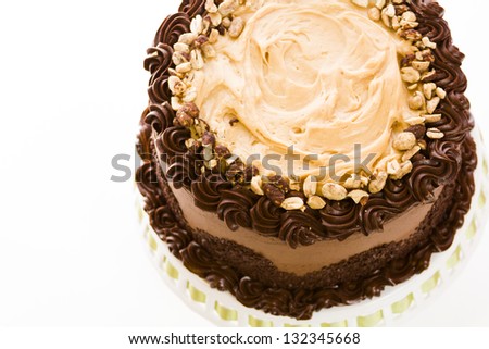 Peanut butter mousse cake with two layers of chocolate cake, filled and topped with peanut butter mousse and covered in chocolate buttercream.