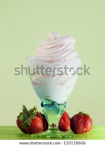 Cup of strawberry frozen yogurt or soft serve ice cream with fresh fruit.