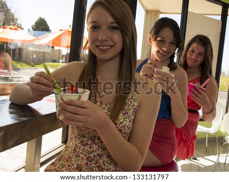 Teenage girls eating frozen soft serve yogurt.