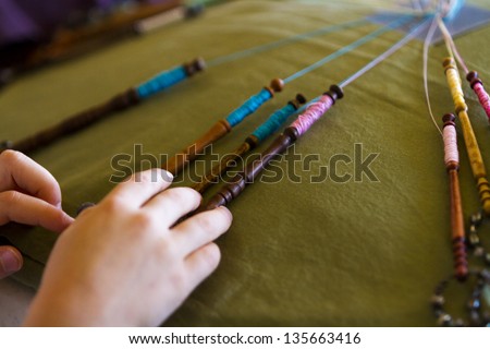 Little girl learning old bobbin lace craft.
