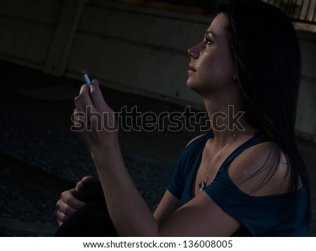 Real young woman smokes on railroad trucks.