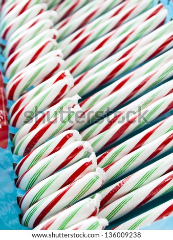White, red and green peppermint candy canes in a box.