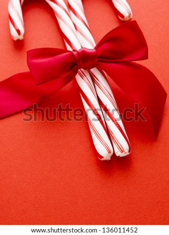 White and red peppermint candy canes on red background.