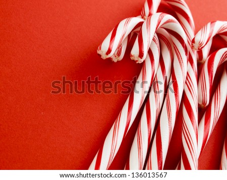 White and red peppermint candy canes on red background.