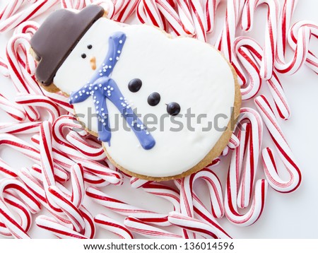 Gourmet snowman cookies with peppermint candy cane on white background.
