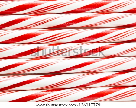 White and red peppermint candy canes in a row on white background.