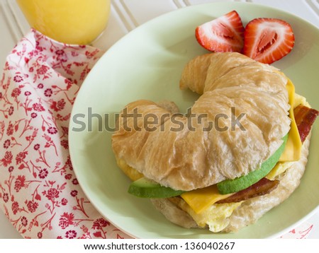 Croissant breakfast sandwich with orange juice served for breakfast.