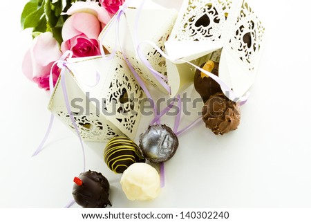 Square white decorative lace heart favor boxes filled with gourmet truffles.