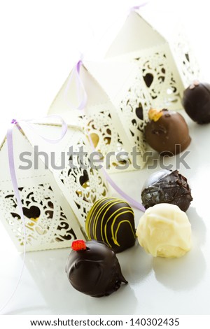 Square white decorative lace heart favor boxes filled with gourmet truffles.