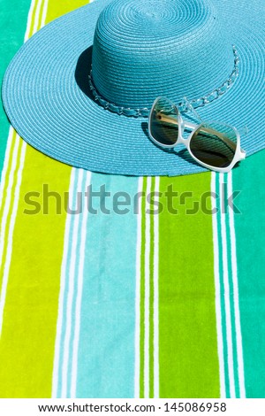 Summer hat with sunglasses on a beach towel.
