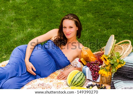 Pregnant woman having a picnic in the park.