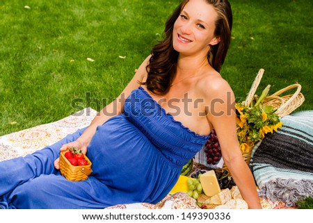 Pregnant woman having a picnic in the park.