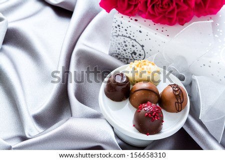 Gift box of assorted gourmet chocolate truffles on silver silk.