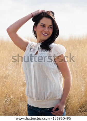 Young woman  standing in field of tall prairie grass.