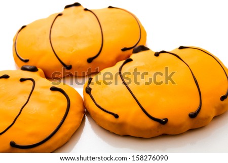 Sugar cookies with orange icing shaped like a pumpkin.