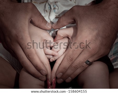 Young family's hands in shape of heart.