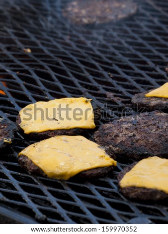 Hamburgers being flame broiled on the gas grill. Shallow depth of field.