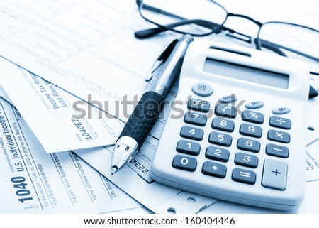 Calculating numbers for income tax return with pen and calculato