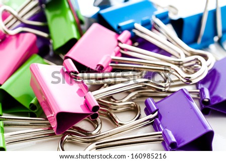 Multicolored paper clips in a pile on a white background.