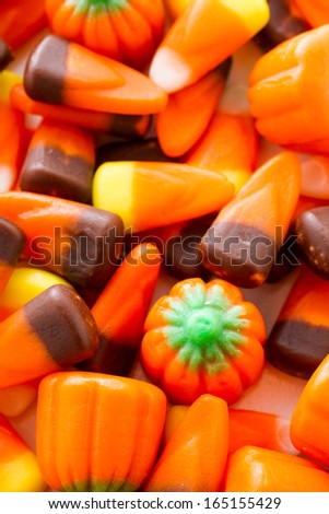Halloween candy-corn and pumpkins in a pile.