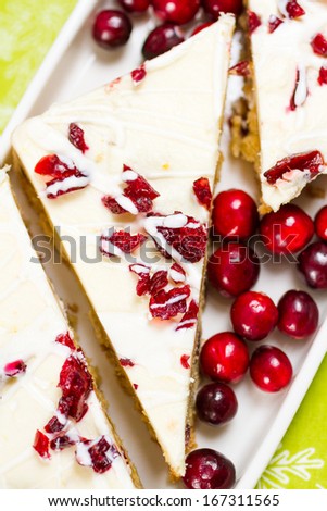 Cranberry bliss bar made with chunks of white chocolate and dried cranberries, topped with sweet cream cheese icing.
