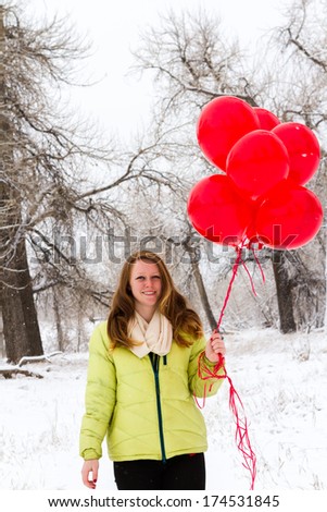 Teenager girl with red balloons walking in the park.