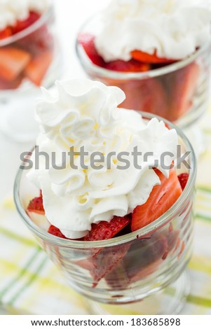 Fresh strawberries with whippes in glass bowls cream for dessert.