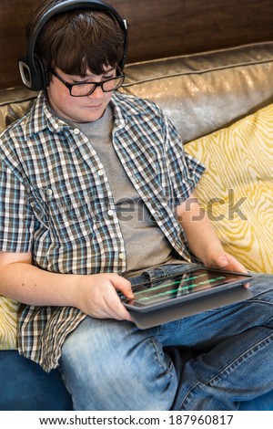 Teenage boy playing with his computer gadgets at leisure time.
