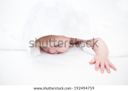 Cute baby girl playing on a white blanket.