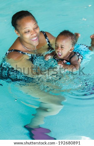 Cute baby girl learning how to swim in indoor pool.