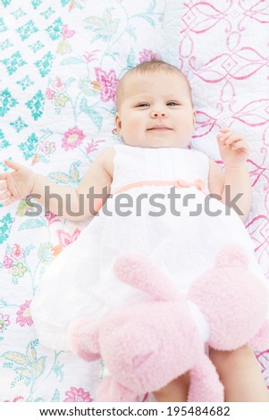 Cute baby girl playing on blanket in the park.
