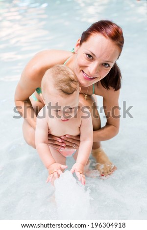 Baby playing in the water at indoor wsimming pool.