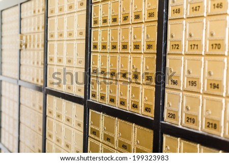 Rows of gold post office boxes with one open mail box.
