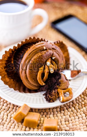 Caramel crunch chocolate cupcake with caramel frosting topped with seasalt and pretzels.