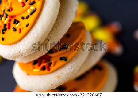Halloween sugar cookies with oranges icing and sprinkles on top.