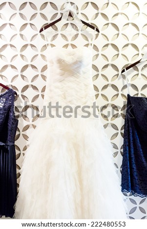 Wedding dress hanging on a white wall with pattern.