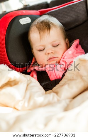 Cute baby girl sleeping in her car seat while traveling in the car.