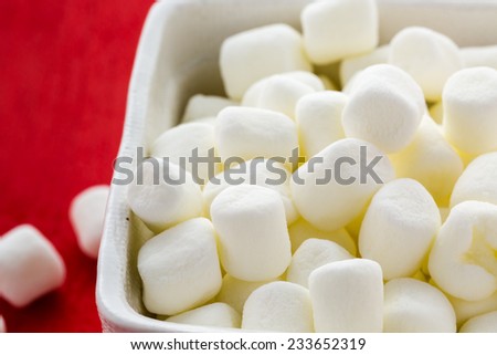 Small round white marshmallows on red backgrouns.