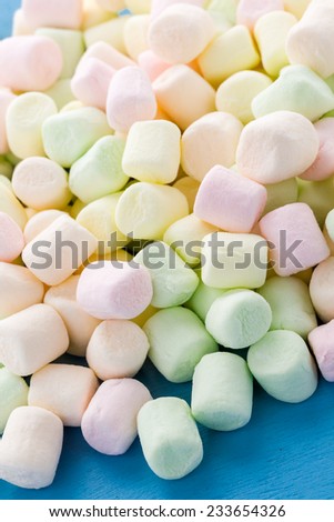 Small round multicolor marshmallows on blue backgrouns.