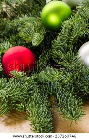Bright Christmas ornaments on live evergreen branches.