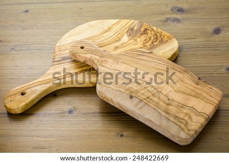 Olive wood cutting board on wood table.