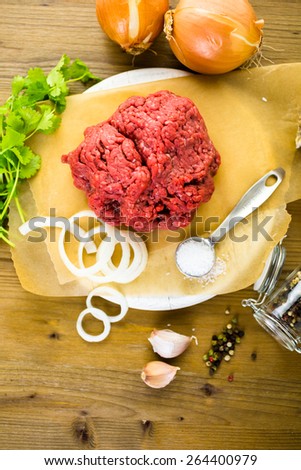 Ground beef on the table with other ingredients for recipe.