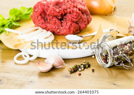 Ground beef on the table with other ingredients for recipe.