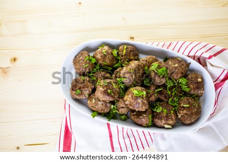 Serving large Italian meatballs in a white serving dish for dinner.