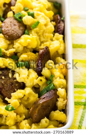 Baked macaroni and cheese with Italian sausage and garnished with chives.