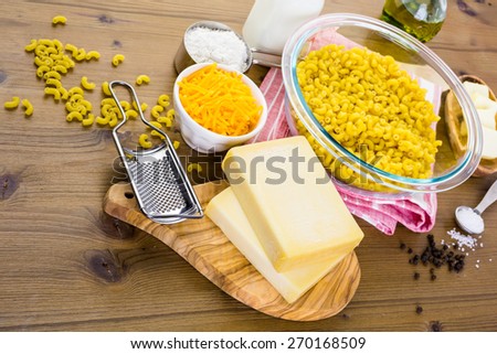 Ingredients for preparing macaroni and cheese on a wood table.