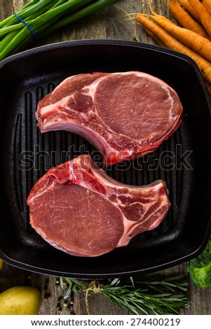 Organic pork lion chops of thick cut on cast iron frying pan.