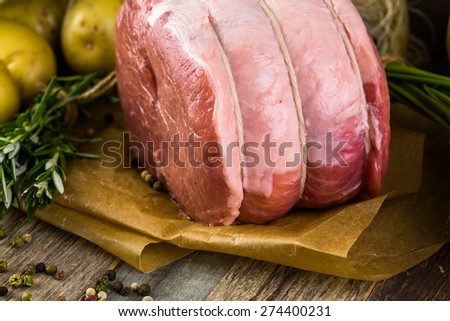 Organic pork lion roast with rosemary on wood farm table.