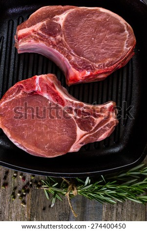 Organic pork lion chops of thick cut on cast iron frying pan.