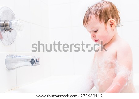 Baby girl having a good time during the bath time.